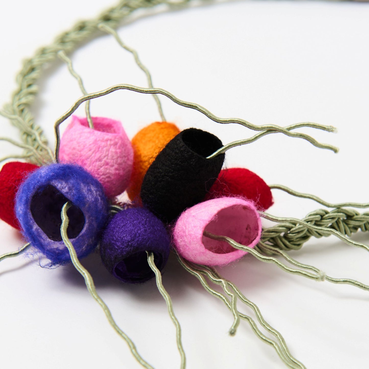 Handcrafted statement necklace featuring a braided green cord with a cluster of colourful, silk cocoons-like ornaments and wire tendrils, secured with a metal clasp.