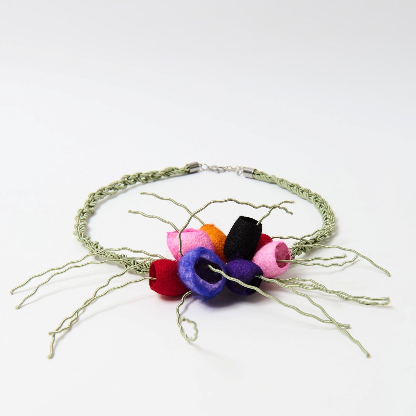 Handcrafted statement necklace featuring a braided green cord with a cluster of silk cocoons secured with a metal clasp.