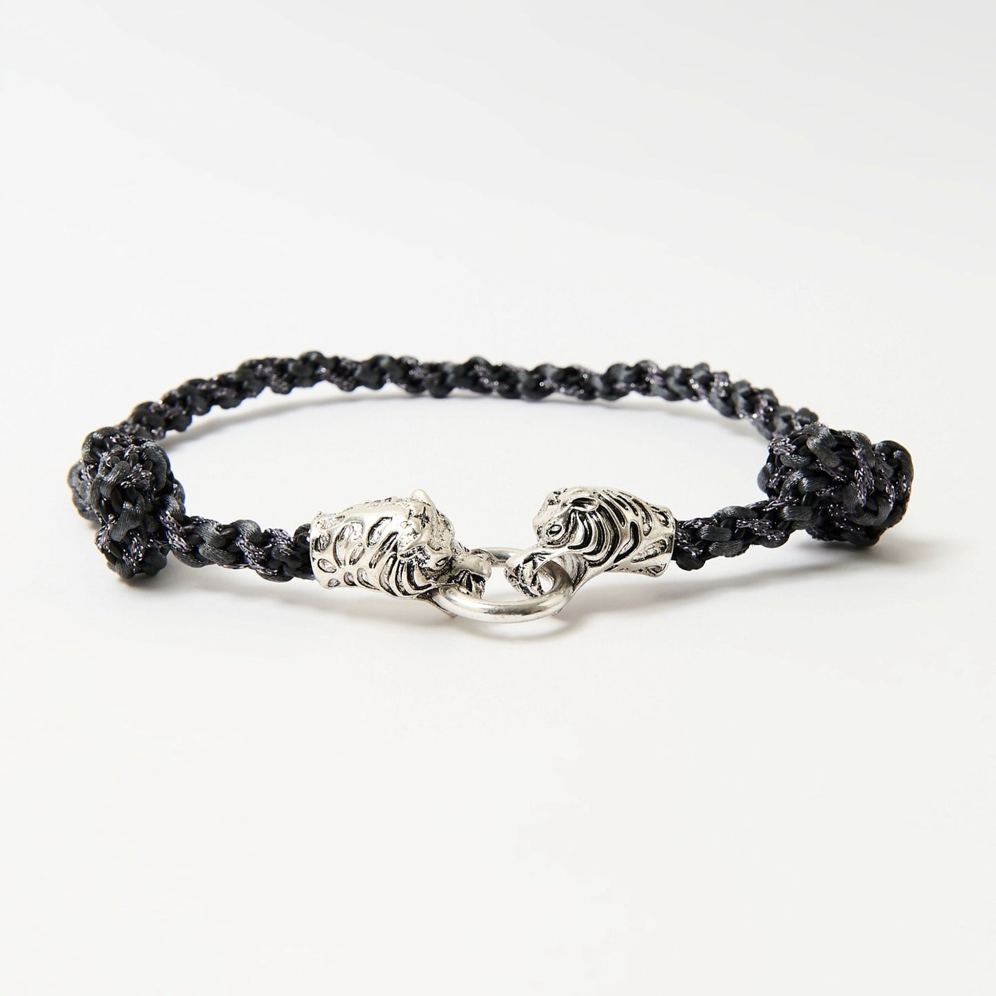 Angled view of a black wave-braided necklace showing the dimensional texture of the cord and the detailed silver tiger clasp.