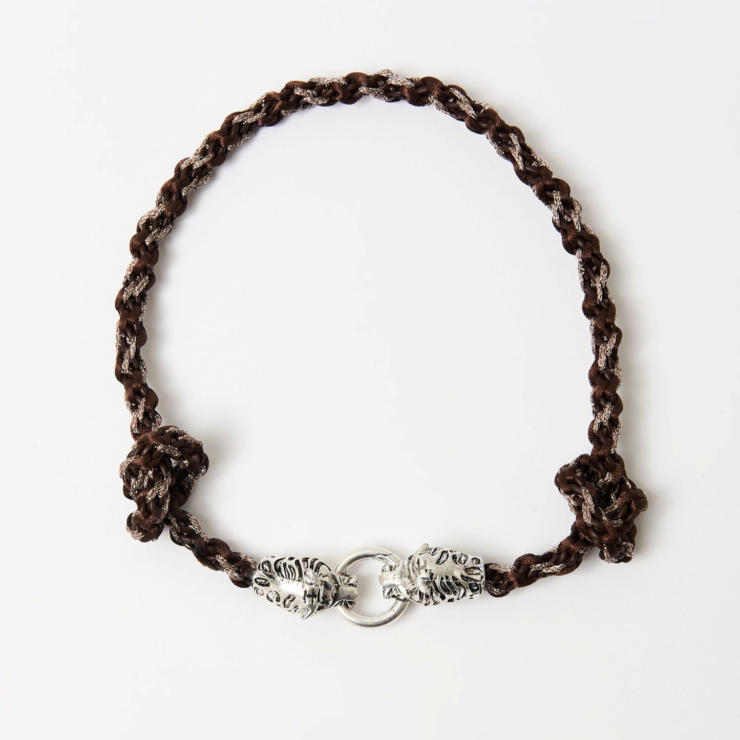 Top-down view of a braided necklace in dark brown tones with a silver tiger head clasp and knot detailing on each side.