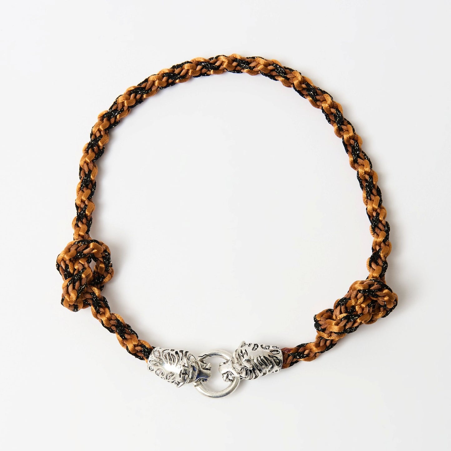 Top-down view of a braided necklace in warn orange tones with a silver tiger head clasp and knot detailing on each side.