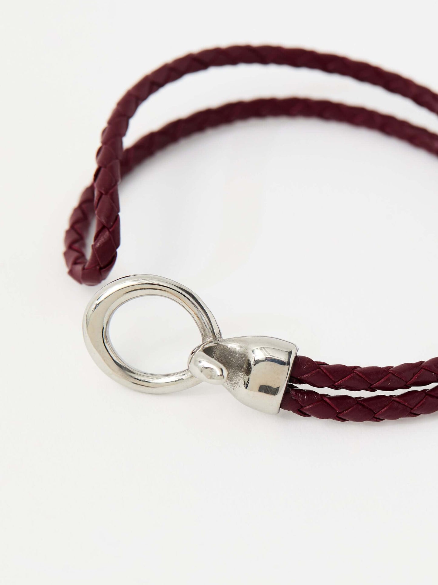 Closeup of red braided leather bracelet with a sleek silver loop and knot clasp, showcasing a modern and minimalist style.