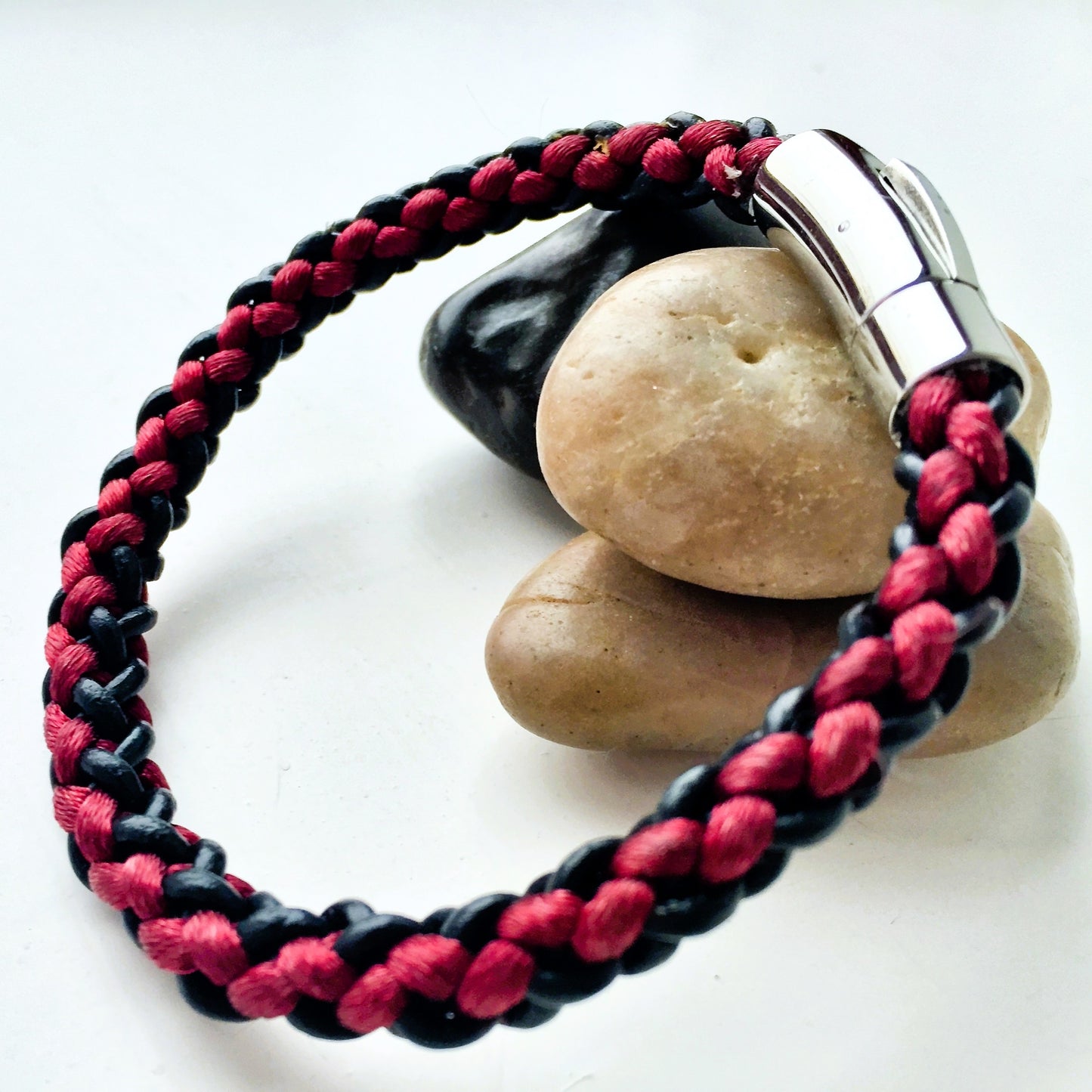 Bracelet with red and black braided design on a white background
