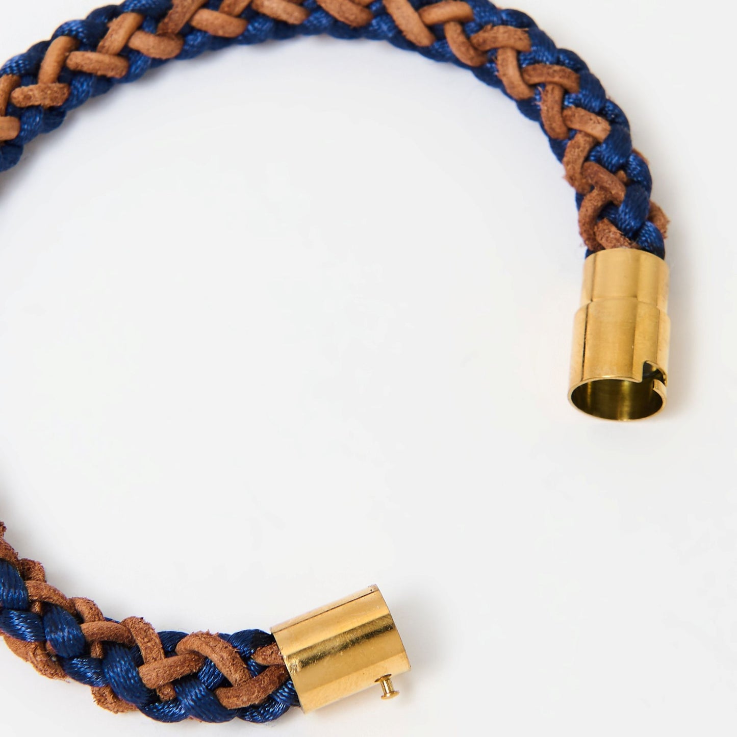 Close-up of artisan-crafted men’s bracelet with navy blue and brown braided leather and polished gold magnetic clasp — modern accessory with timeless appeal.