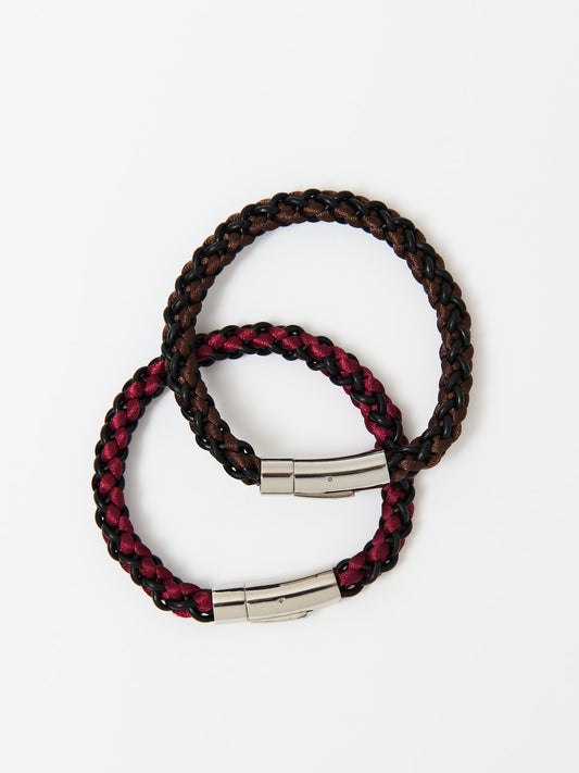 Two braided bracelets, one featuring brown and black tones and the other red and black, both with stainless steel magnetic clasps, elegantly intertwined and displayed on a white background.