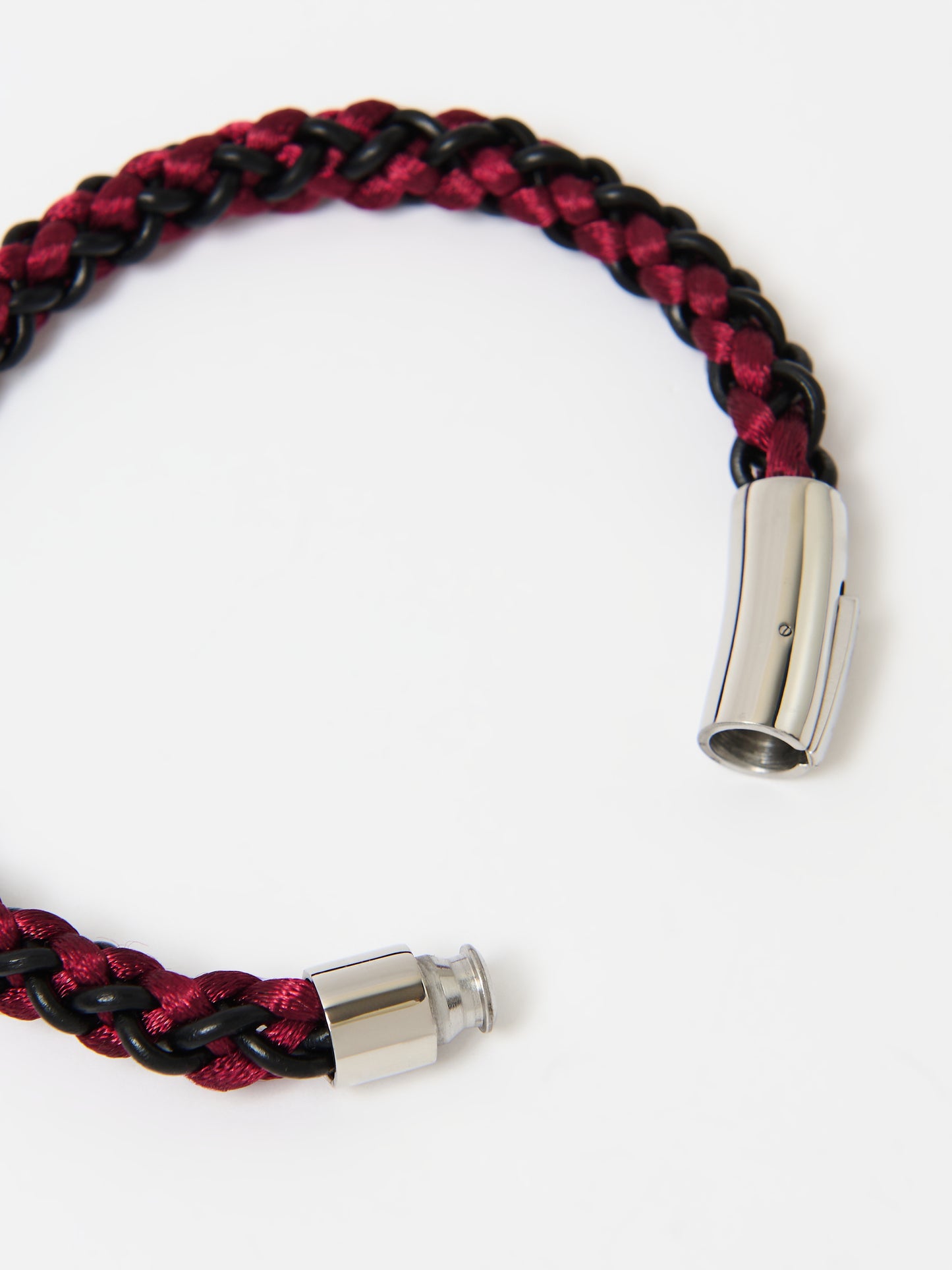 Close-up of a braided bracelet featuring intertwined red and black materials with stainless steel magnetic clasp ends, displayed on a white background.