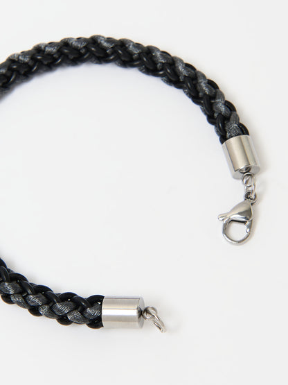 Close-up of a braided bracelet featuring intertwined black and grey materials with stainless steel lobster clasp ends, displayed on a white background.