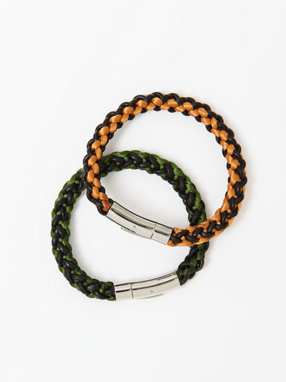 Two braided bracelets, one featuring green and brown tones and the other orange and brown, both with stainless steel magnetic clasps, elegantly intertwined and displayed on a white background.