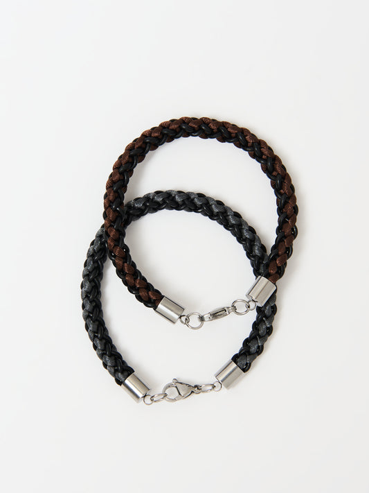 Two braided bracelets, one featuring brown and black tones and the other grey and black, both with stainless steel lobster clasps, elegantly intertwined and displayed on a white background.