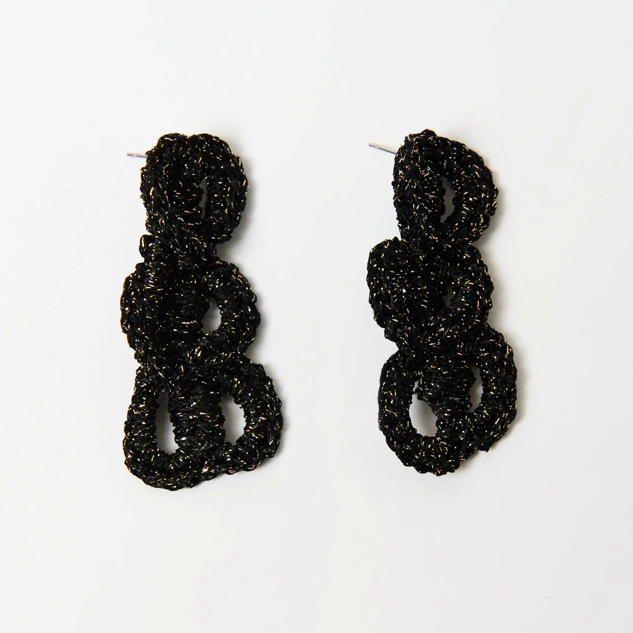 Handmade black and gold loop earrings with metallic yarn catching the light, emphasizing texture and shine.
