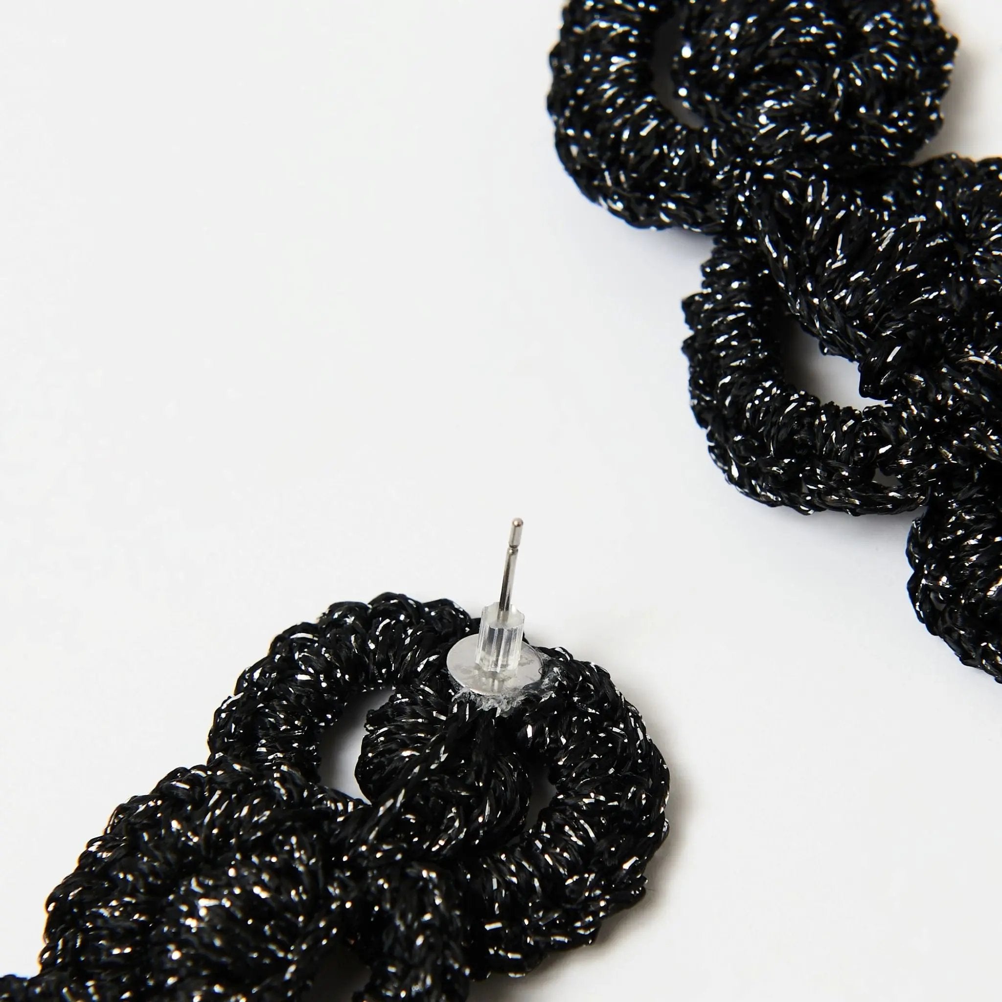 Reverse view of black and silver loop earrings with stud post and transparent silicone backing.