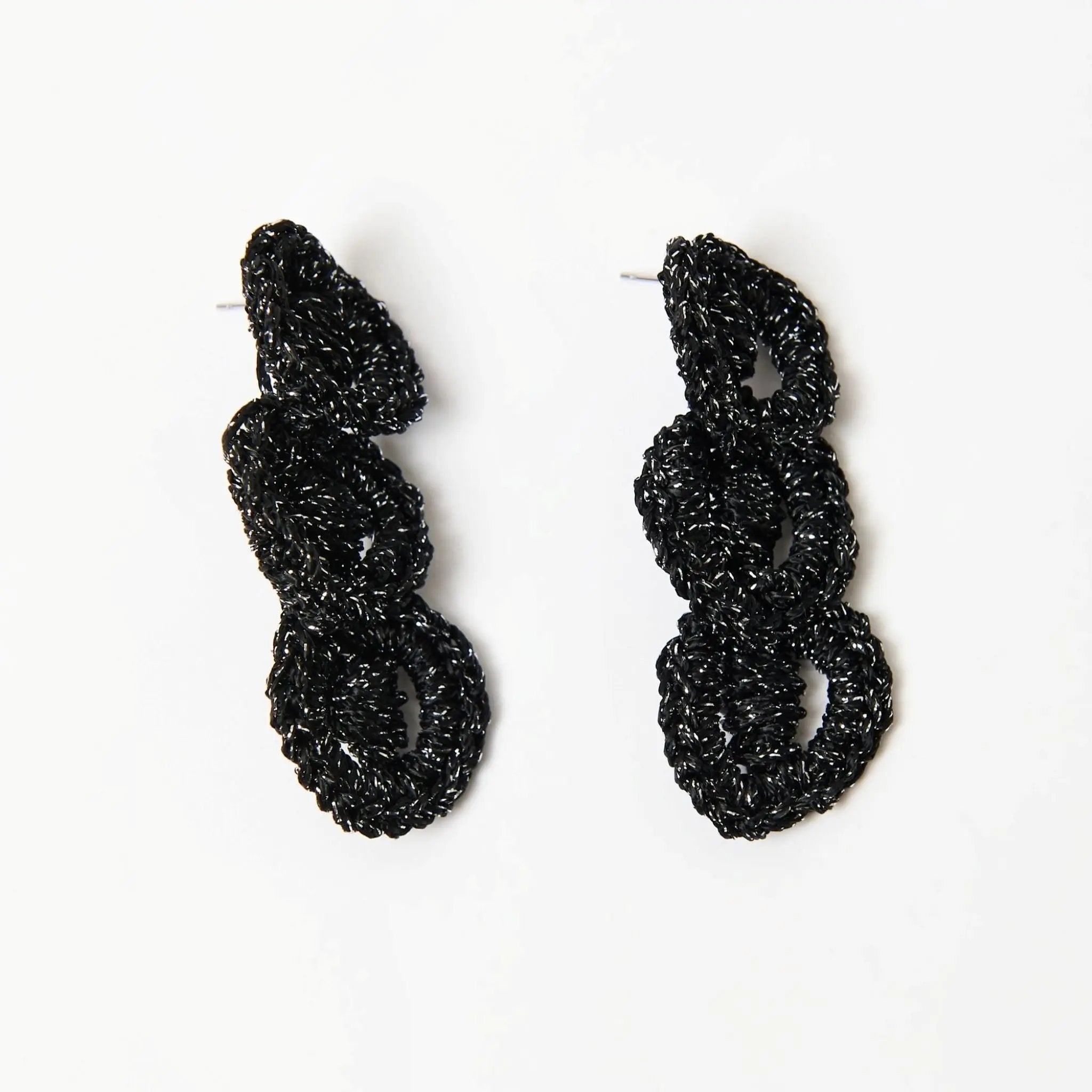 Side angle of black and silver crochet earrings showing sculptural depth and looped construction.