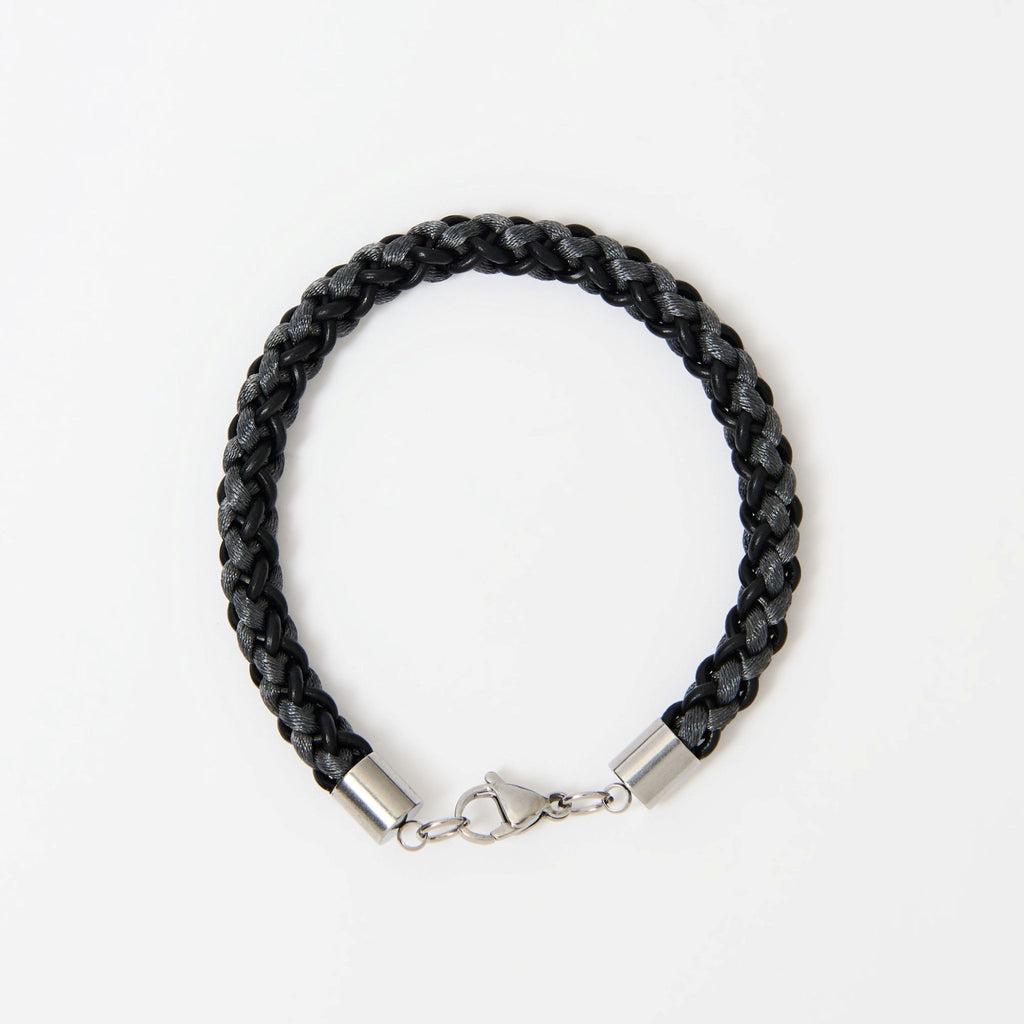 The Marlowe men's braided leather bracelet in Midnight Black with Graphite Grey and a silver lobster clasp, laid flat