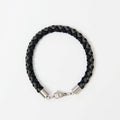 The Marlowe men's braided leather bracelet in Midnight Black with Graphite Grey and a silver lobster clasp, laid flat