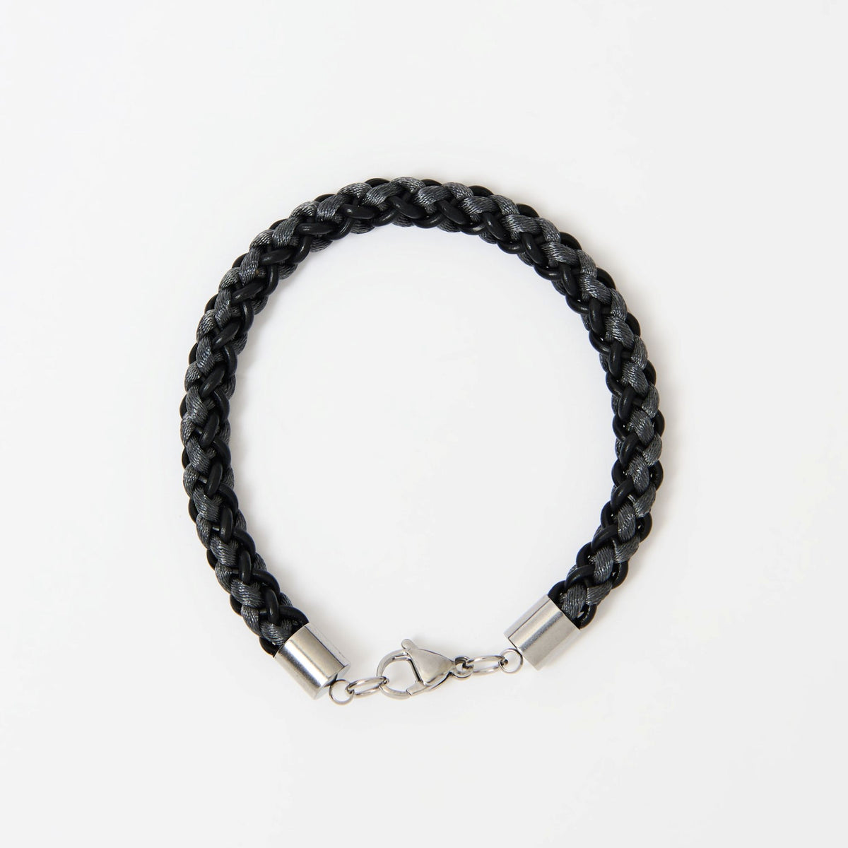 The Marlowe men's braided leather bracelet in Midnight Black with Graphite Grey and a silver lobster clasp, laid flat