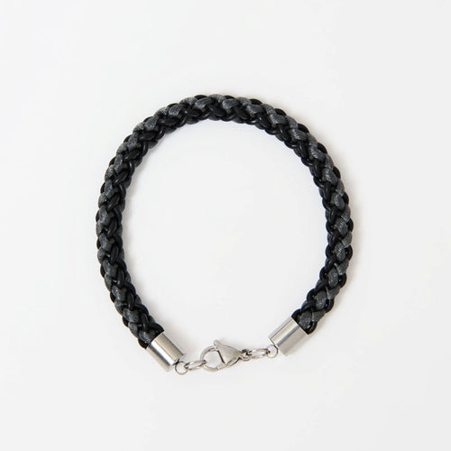 The Marlowe men's braided leather bracelet in Midnight Black with Graphite Grey and a silver lobster clasp, laid flat