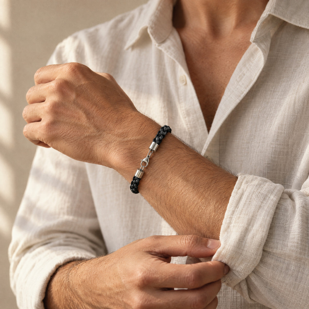 The Marlowe men's braided leather bracelet in Midnight Black with Graphite Grey, silver lobster clasp, worn at the wrist