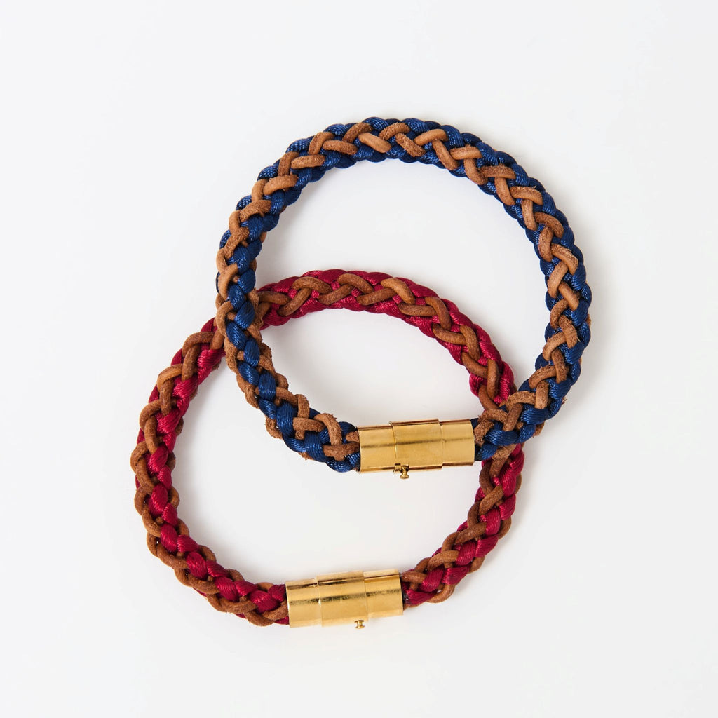 The Vale braided leather bracelets in Crimson Red and Indigo Blue with gold magnetic clasps, laid flat together