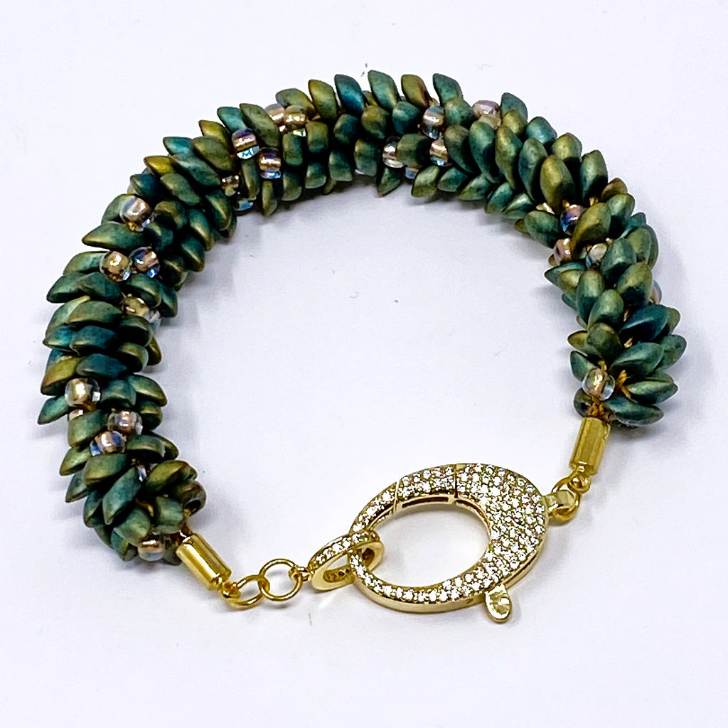 The Elio beaded bracelet in green and gold beads with a crystal-set gold lobster clasp, laid flat on white