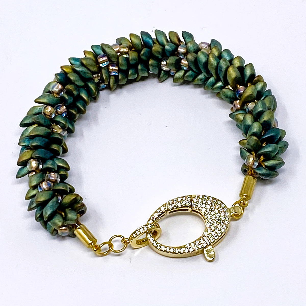 The Elio beaded bracelet in green and gold beads with a crystal-set gold lobster clasp, laid flat on white