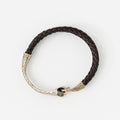 The Serin leather bracelet in Chestnut Brown with a sculptural silver snake clasp, laid flat on white
