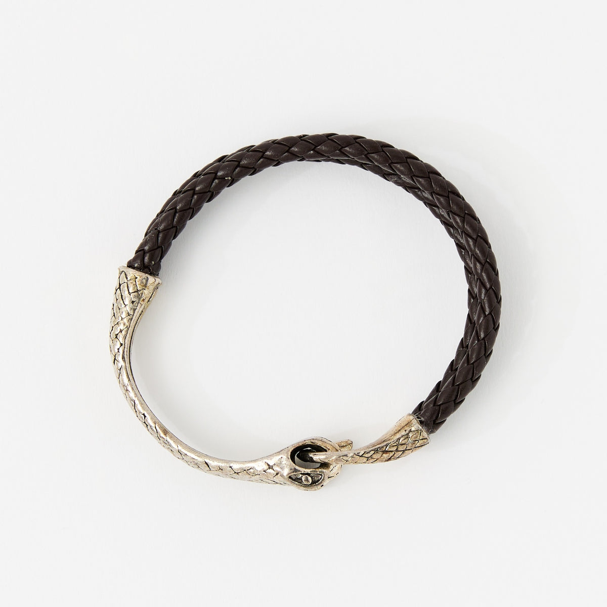 The Serin leather bracelet in Chestnut Brown with a sculptural silver snake clasp, laid flat on white