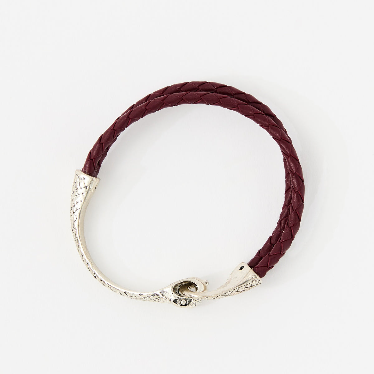 The Serin leather bracelet in Crimson Red with a sculptural silver snake clasp, laid flat on white