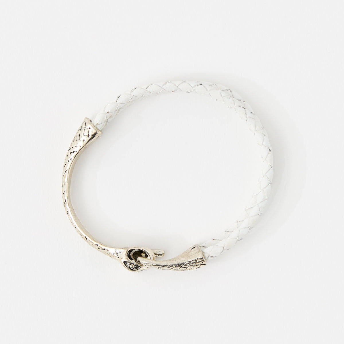 The Serin leather bracelet in Ivory White with a sculptural silver snake clasp, laid flat on white