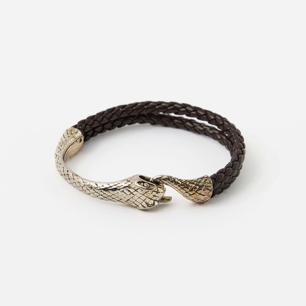 Brown braided leather bracelet with a silver snake head clasp, featuring intricate scale details and a sleek, minimalistic design.