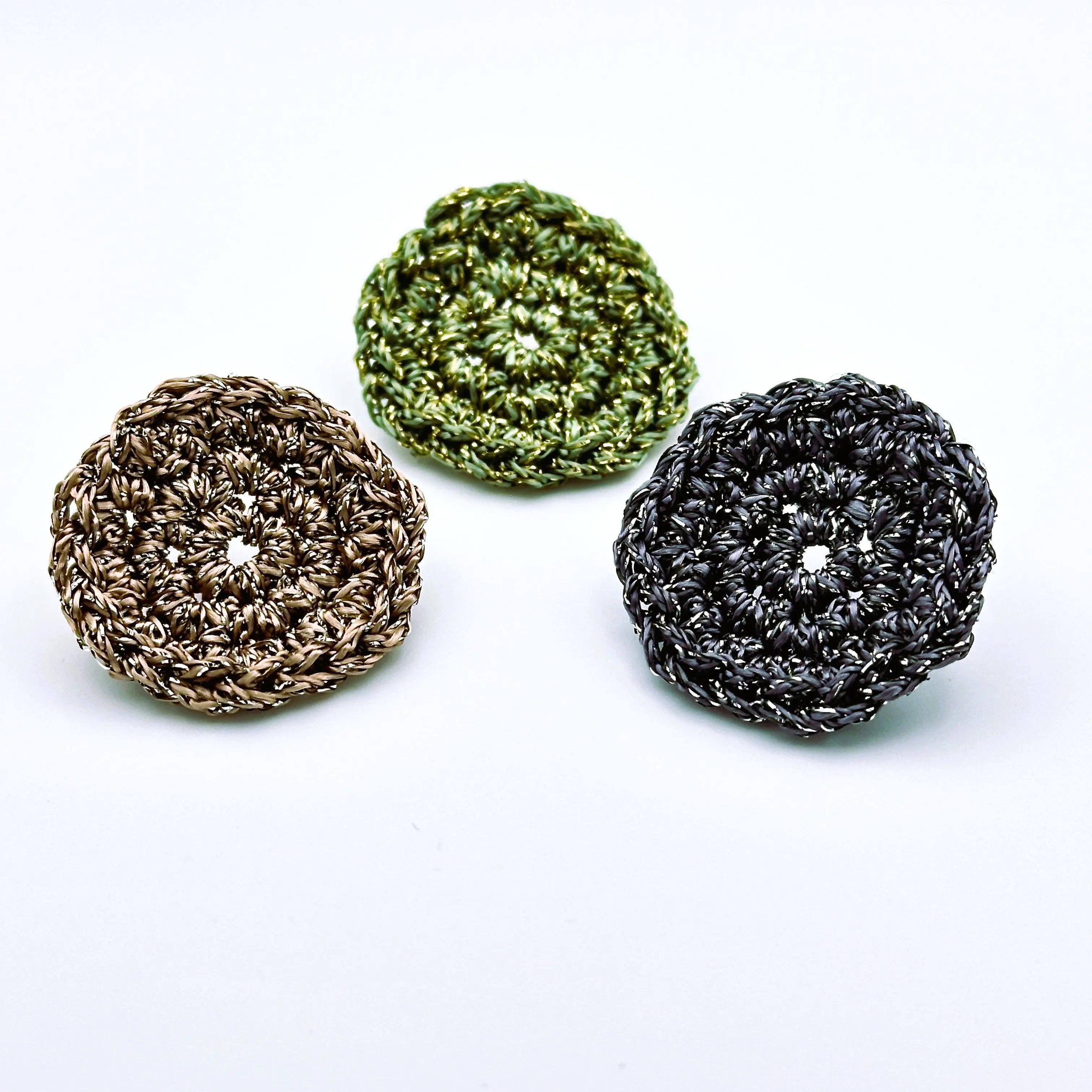 Set of three handcrafted disc earrings in shimmering green, copper, and charcoal grey tones, showcasing a crocheted circular design with metallic thread.