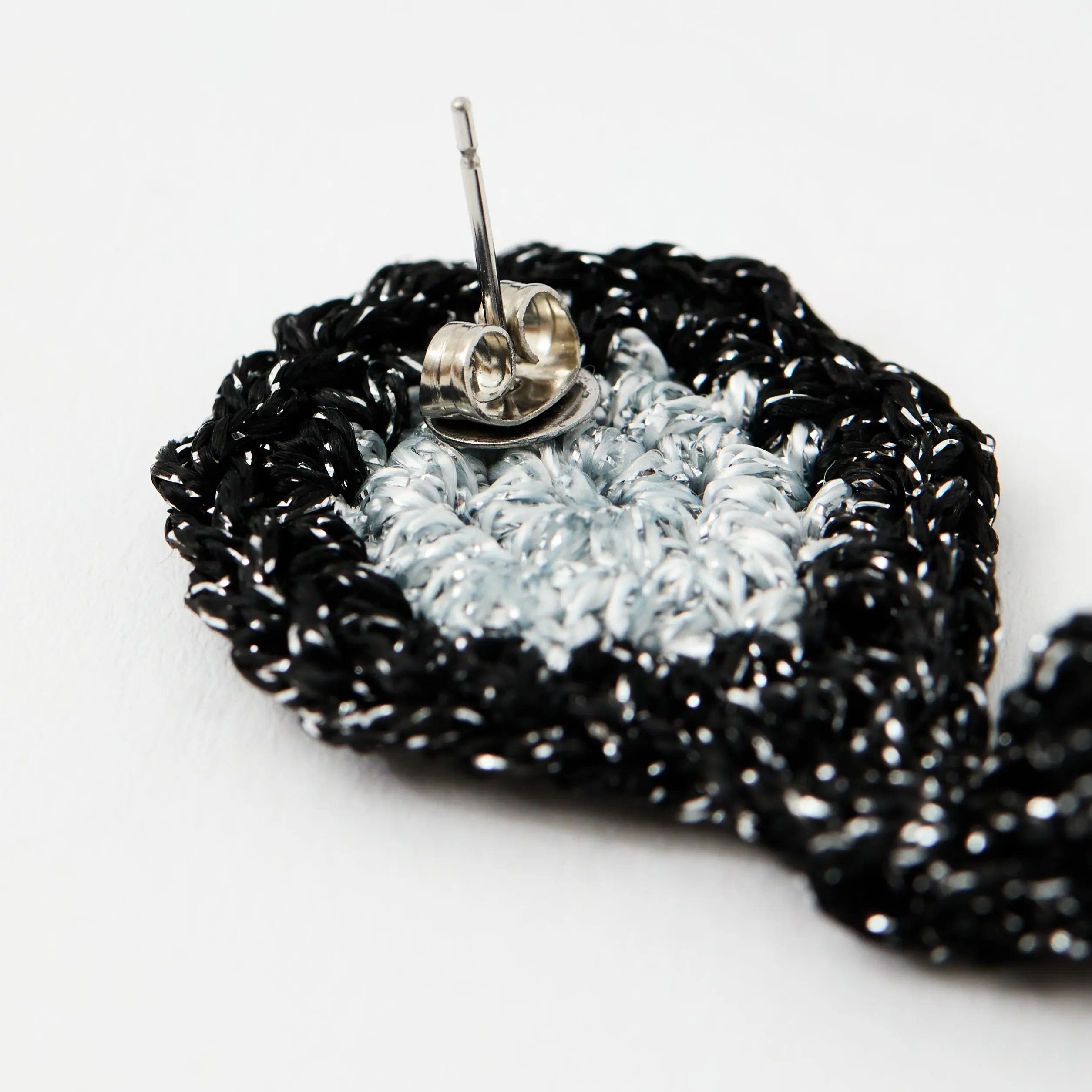 Close-up of silver-tone stud post with secure scroll backing stitched into the silver and black crochet earring.