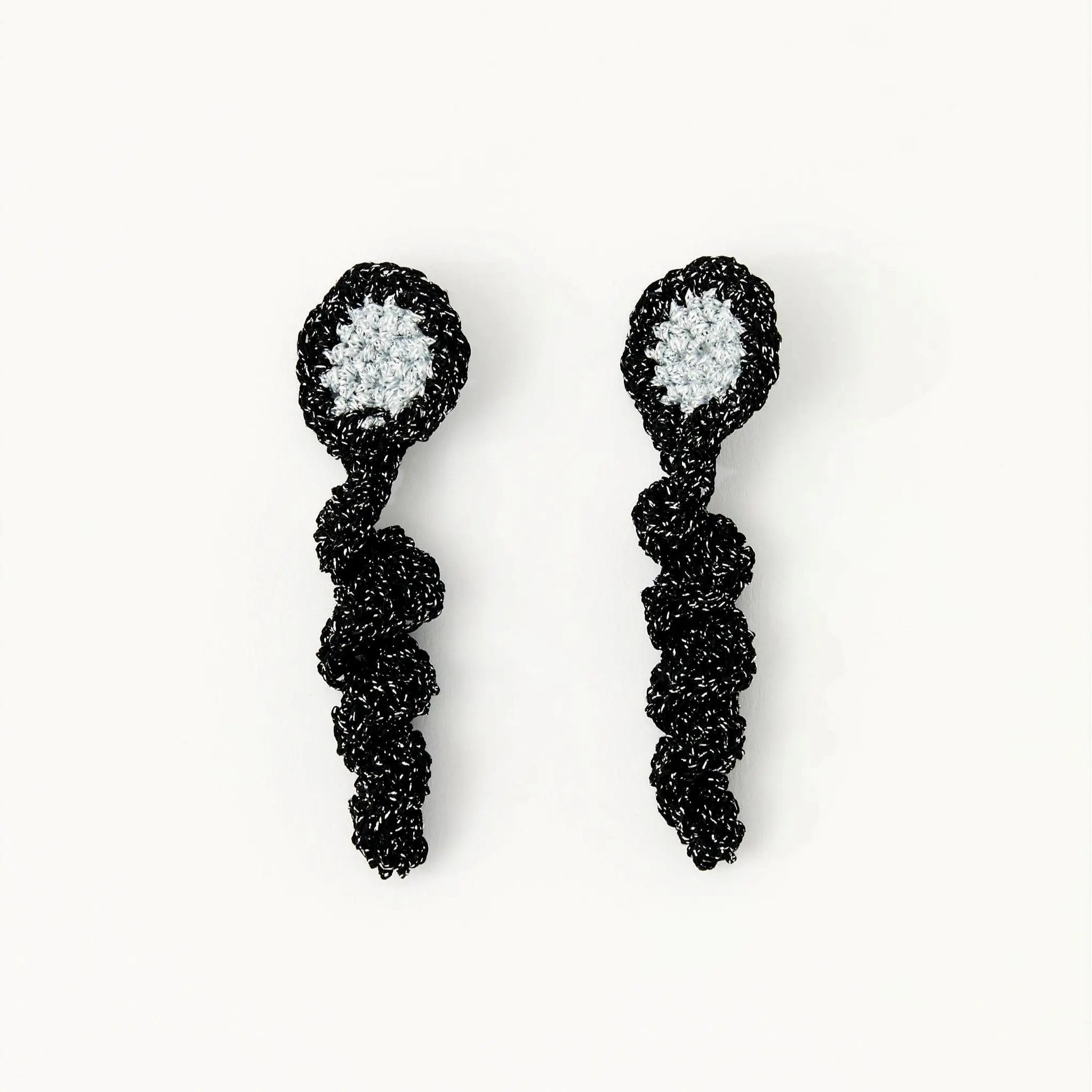 Black frill earrings with shimmering silver disc centre, hand-crocheted and displayed flat on white.