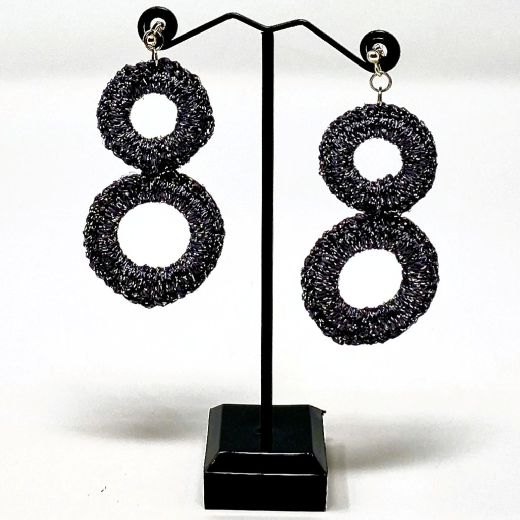 The Sienna charcoal grey crochet double-ring earrings hanging on a black earring stand - Lodorfo
