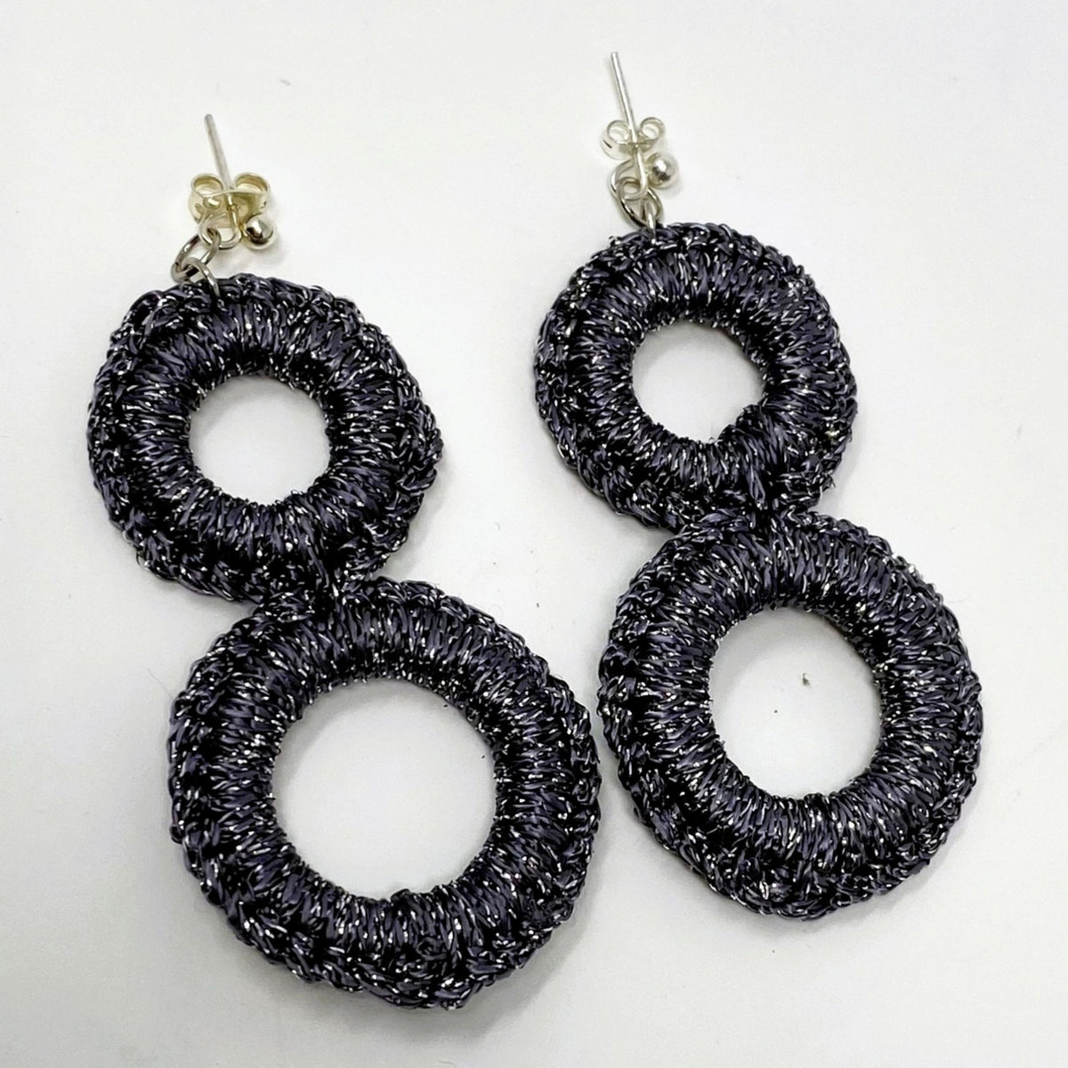 The Sienna charcoal grey crochet double-ring drop earrings with silver sparkle, laid flat - Lodorfo
