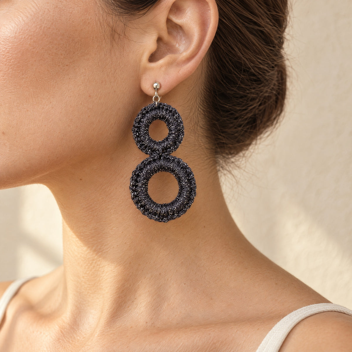 Woman wearing the Sienna charcoal grey crochet double-ring drop earring with silver sparkle, handmade UK - Lodorfo