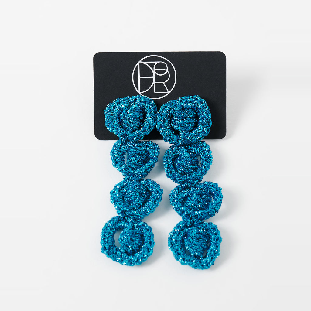 The Arlo long deep teal four-ring crochet loop earrings displayed on a black earring card - Lodorfo