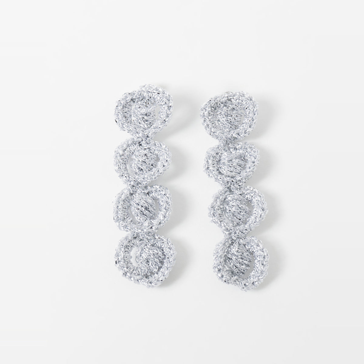 The Arlo long silver grey four-ring crochet loop earrings laid flat - Lodorfo