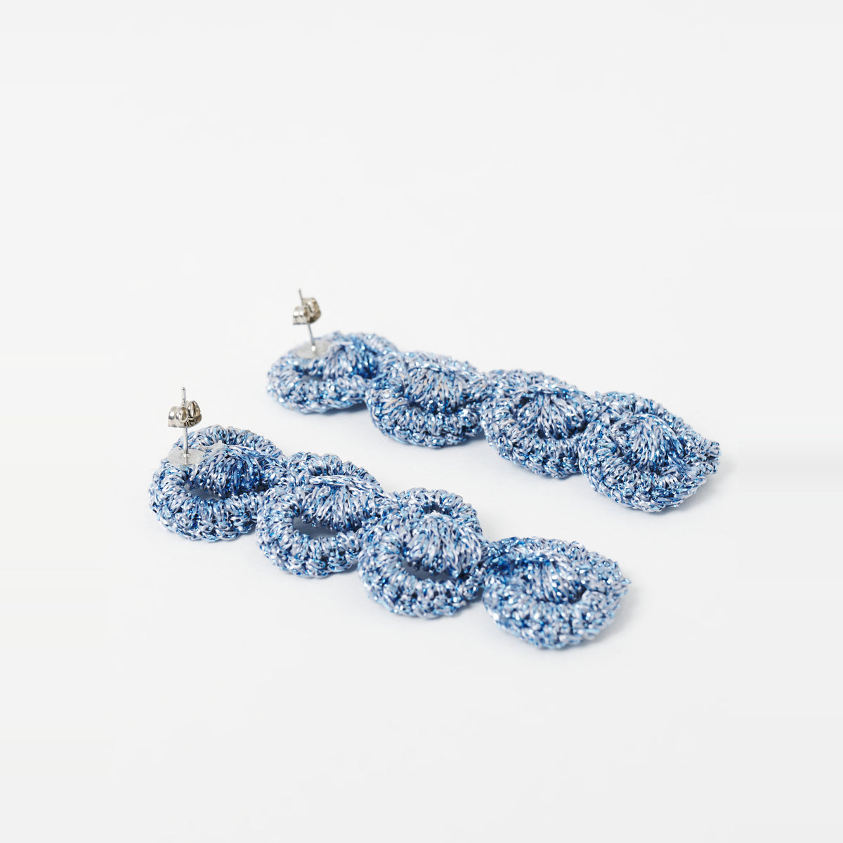 Close-up of the Arlo long sky blue four-ring crochet loop earrings, showing the stud posts - Lodorfo