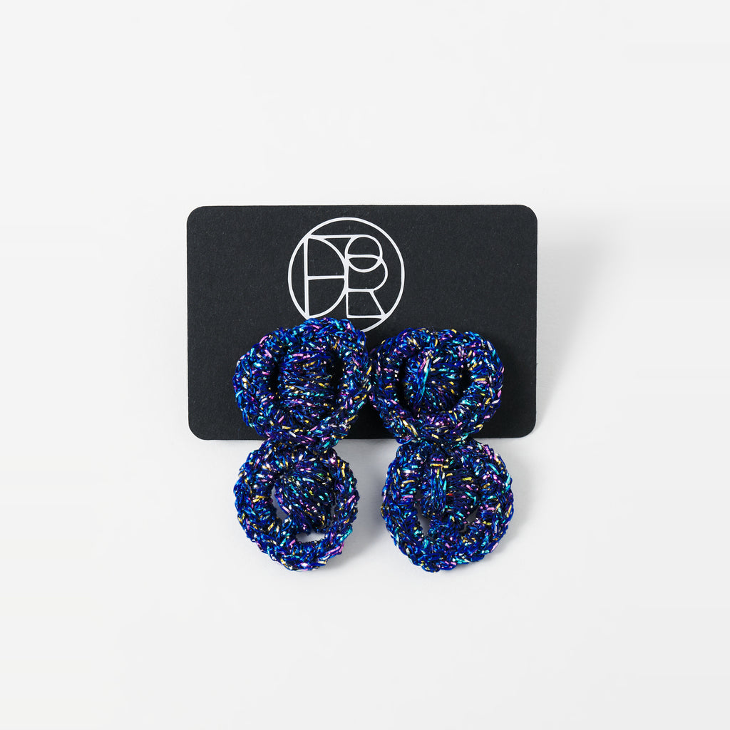 The Arlo short indigo blue two-ring crochet loop earrings displayed on a black earring card - Lodorfo