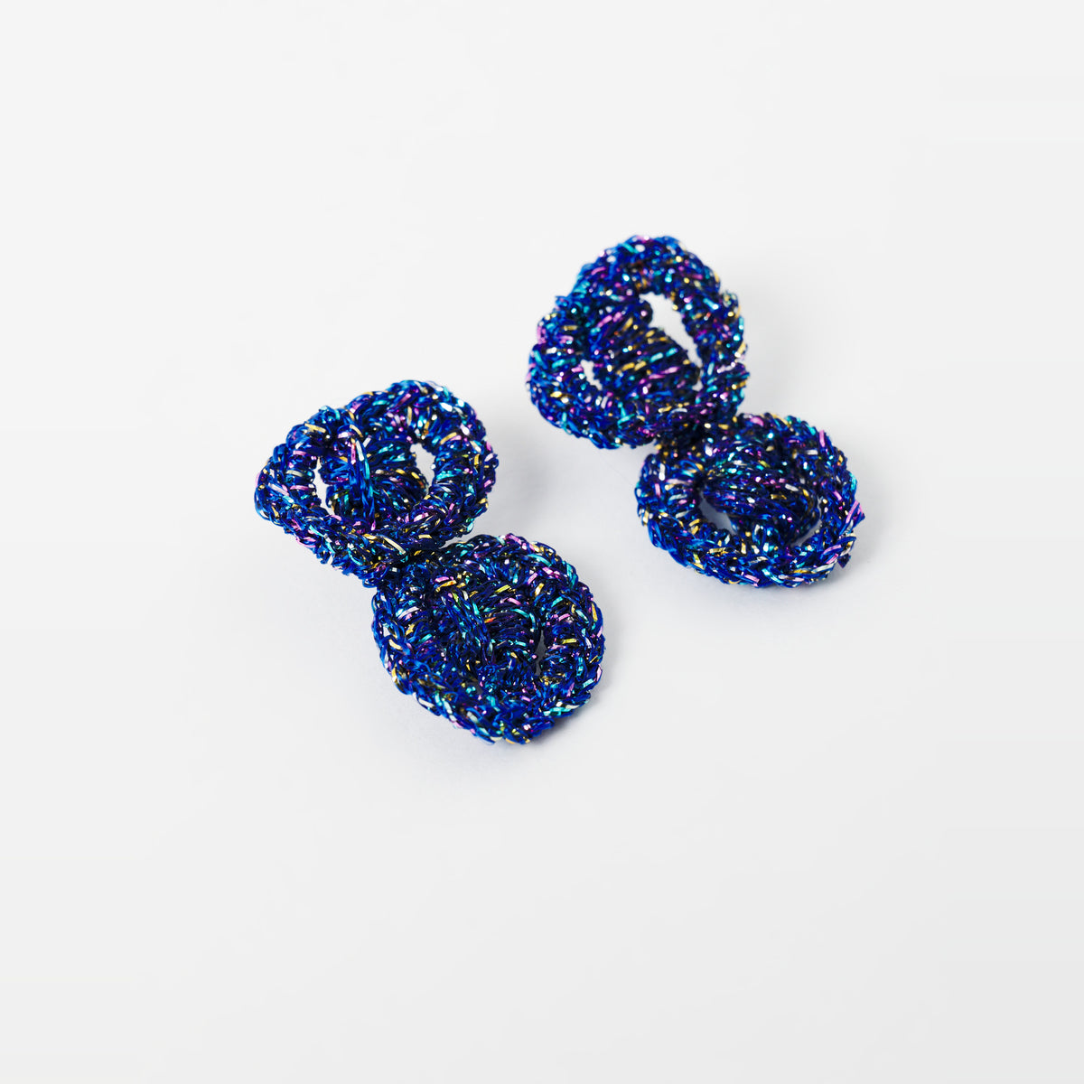 The Arlo short indigo blue two-ring crochet loop earrings in an angled flat lay - Lodorfo