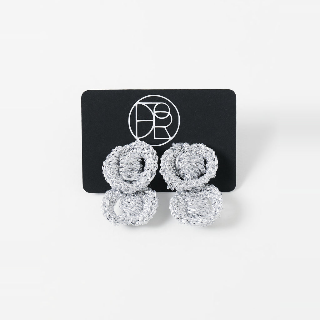 The Arlo short silver grey two-ring crochet loop earrings displayed on a black earring card - Lodorfo