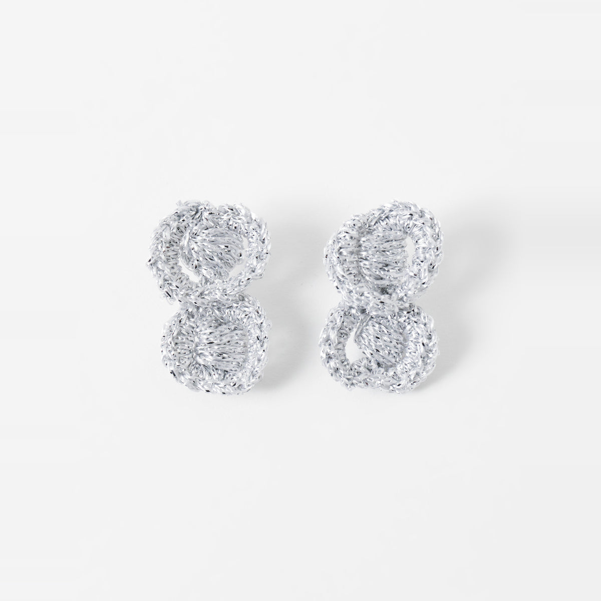 The Arlo short silver grey two-ring crochet loop earrings laid flat - Lodorfo