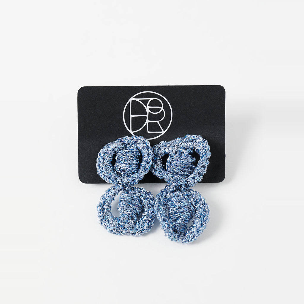 The Arlo short sky blue two-ring crochet loop earrings displayed on a black earring card - Lodorfo
