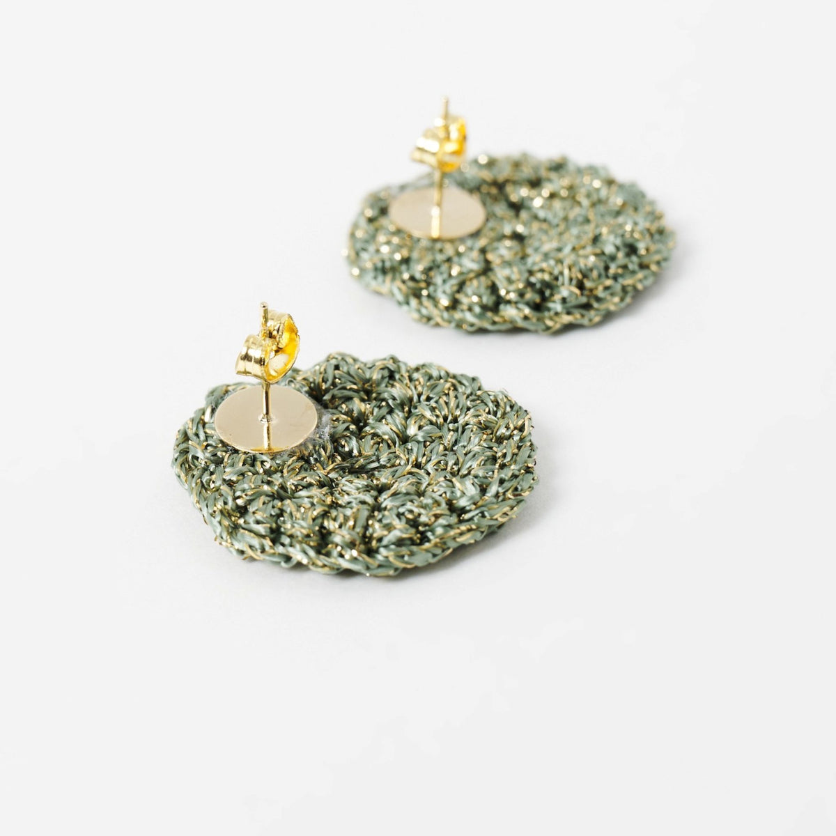 Close-up of the hand-crocheted texture of the Vela disc earrings in forest green with gold shimmer - Lodorfo