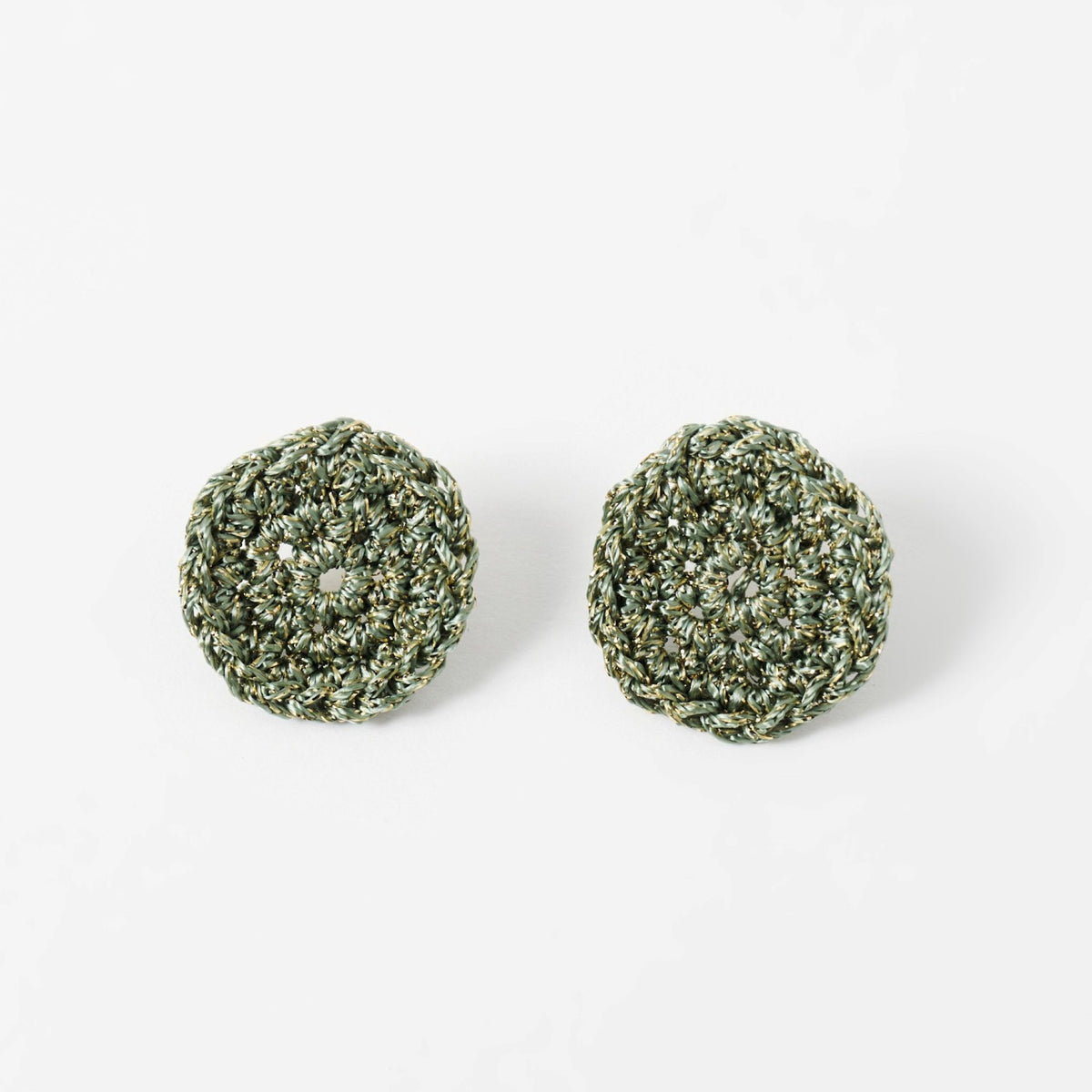 The Vela crochet disc earrings in forest green with gold shimmer, flat lay - Lodorfo