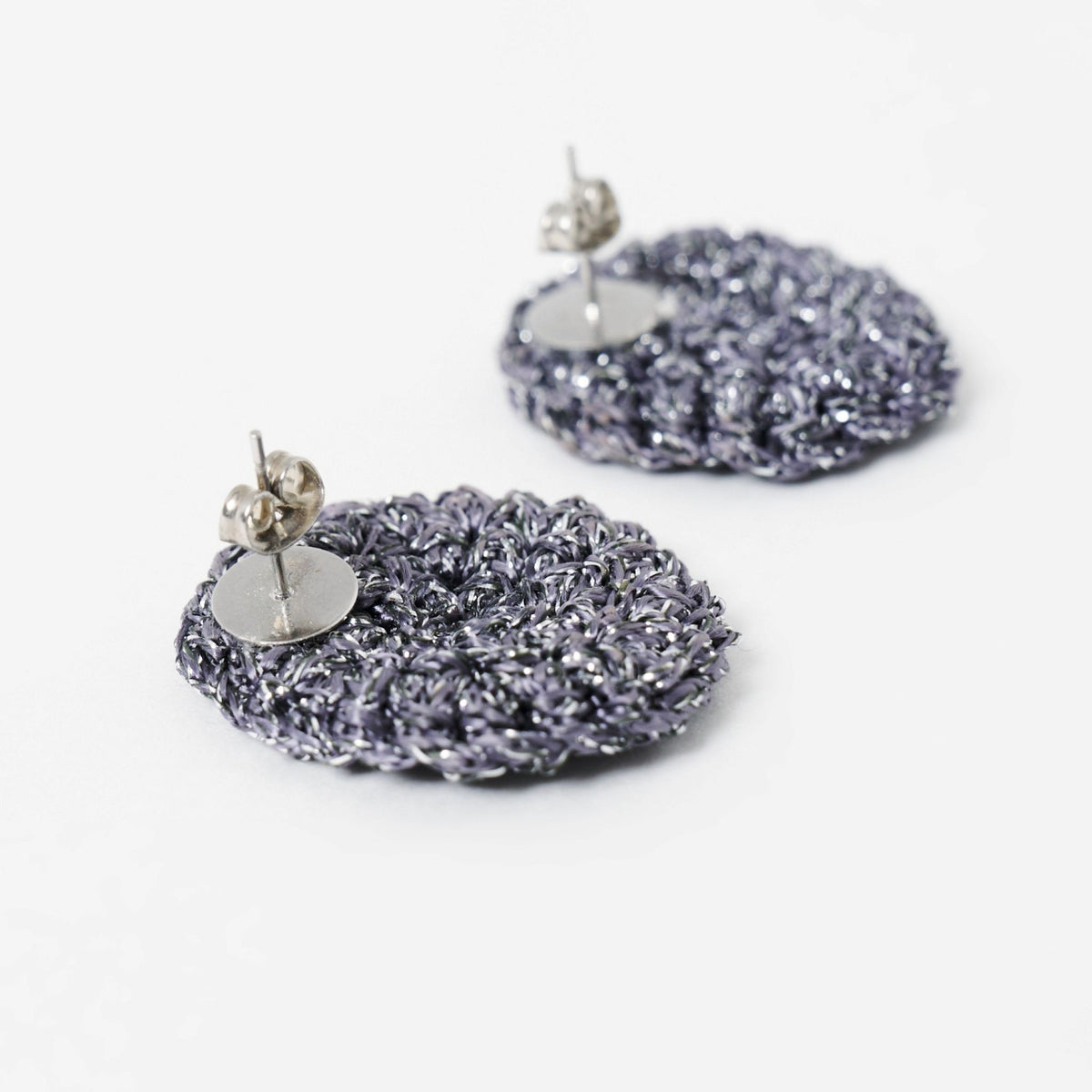 Close-up of the hand-crocheted texture of the Vela disc earrings in graphite grey with silver shimmer - Lodorfo