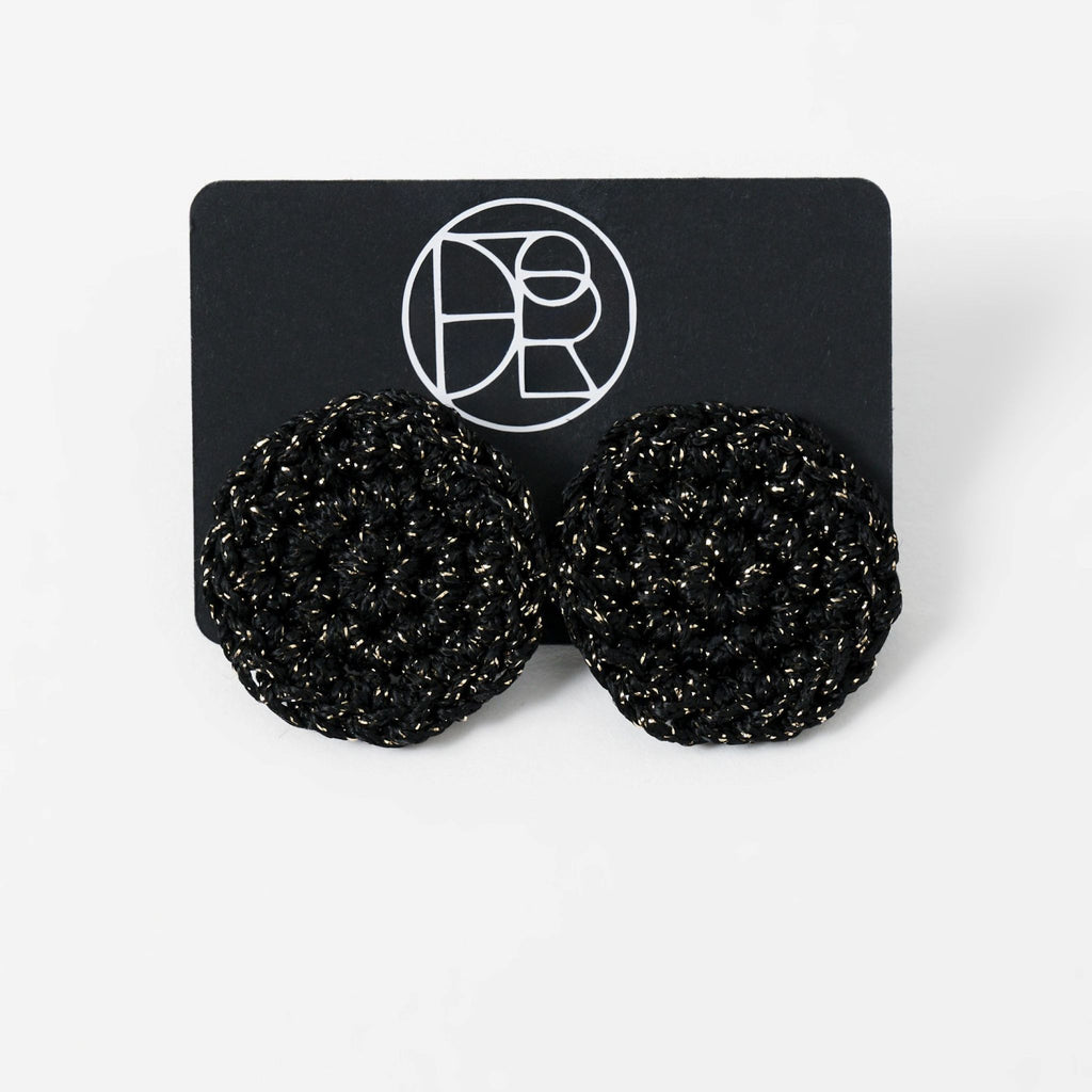 The Vela crochet disc earrings in midnight black with gold shimmer, styled display - Lodorfo