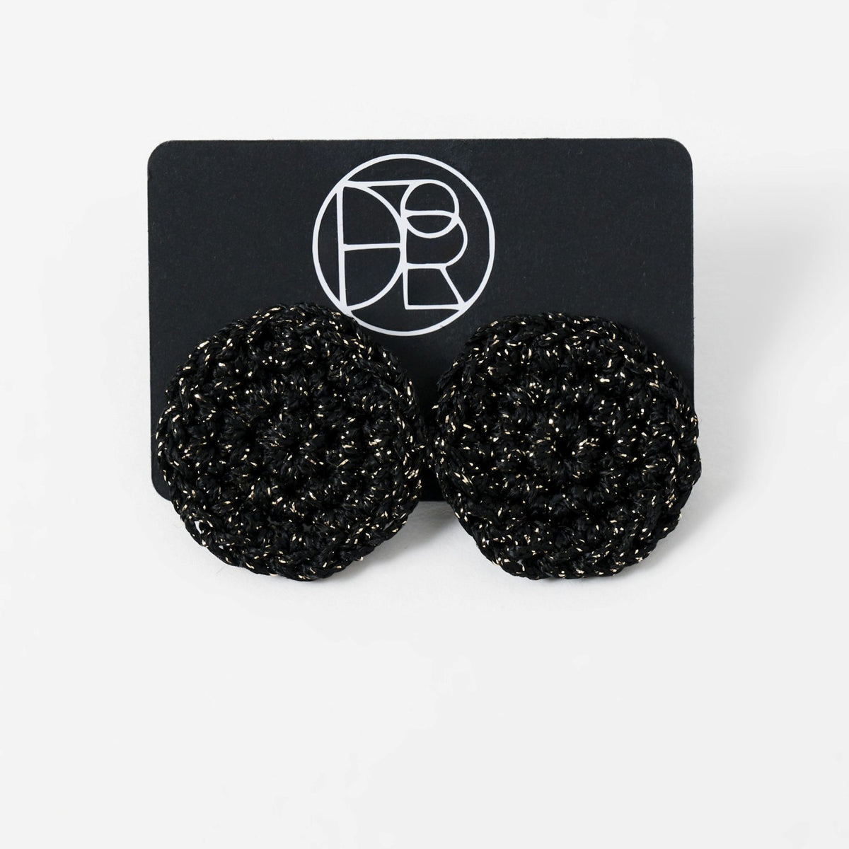The Vela crochet disc earrings in midnight black with gold shimmer, styled display - Lodorfo