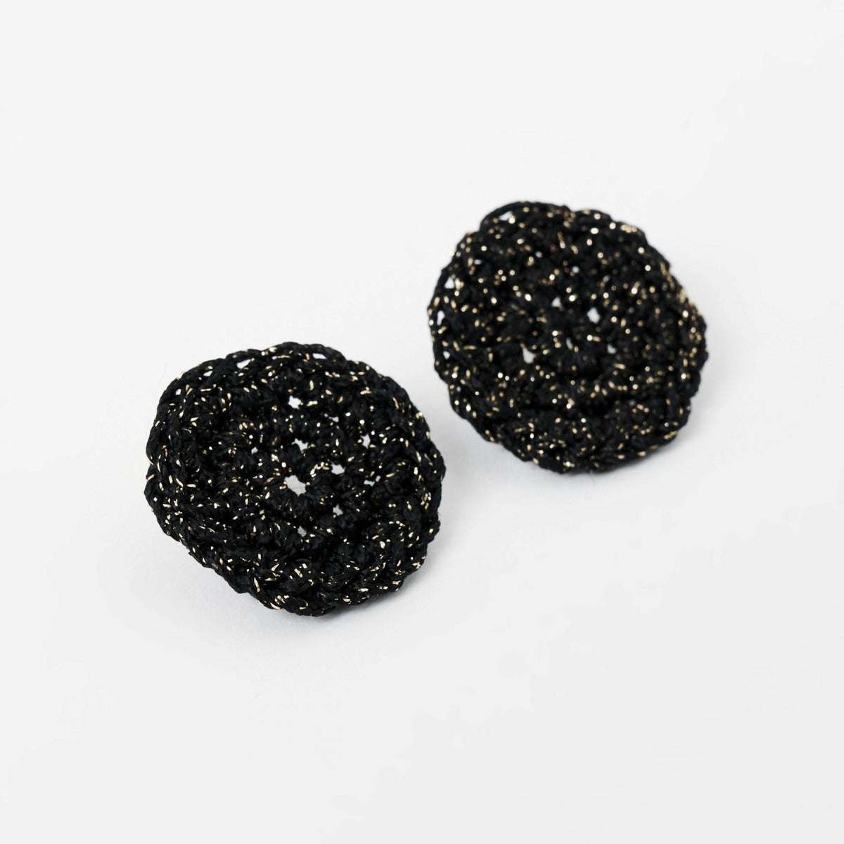 The Vela crochet disc earrings in midnight black with gold shimmer, flat lay, second view - Lodorfo