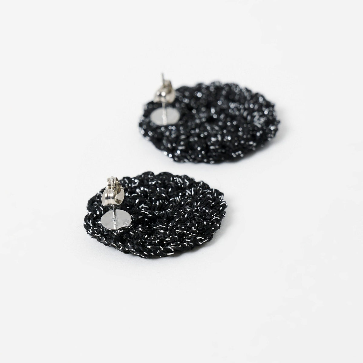 Close-up of the hand-crocheted texture of the Vela disc earrings in midnight black with silver shimmer - Lodorfo